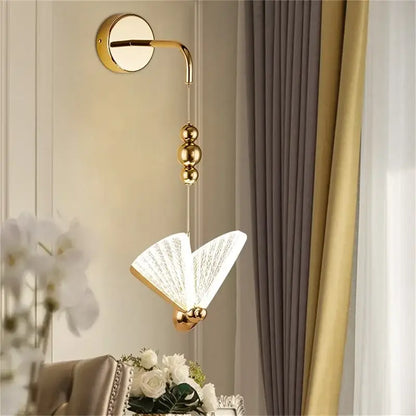 Modern gold decorbites butterfly wall light features a gold-finished sconce with an open-book glass lampshade for bedrooms