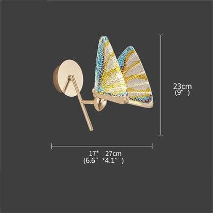 Gold-toned decorbites butterfly wall sconce with blue yellow white mosaic glass wings for modern bedroom lighting