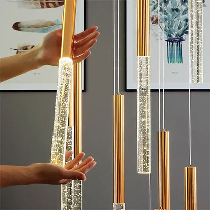 Modern gold decorbites crystal staircase chandelier features gold-toned cylindrical pendant lights with warm led illumination
