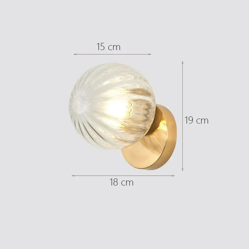 Modern gold decorbites glass ball wall lamp with a translucent ribbed glass globe and warm brass base for bedroom sconce