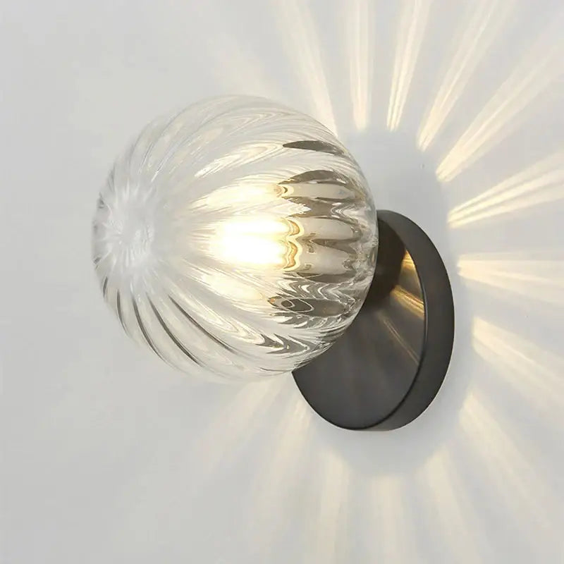 Modern gold decorbites glass ball wall lamp with clear ribbed glass globe and black metal base for bedroom sconce