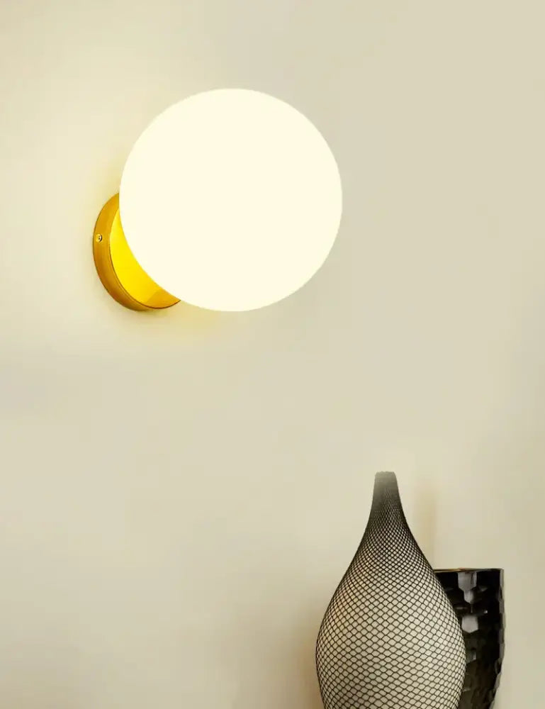 Modern gold decorbites glass ball wall lamp featuring a frosted white spherical glass shade for bedroom sconce use
