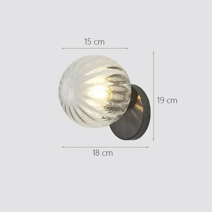 A modern wall lamp featuring a decorbites glass ball wall sconce with a textured glass globe and black circular base