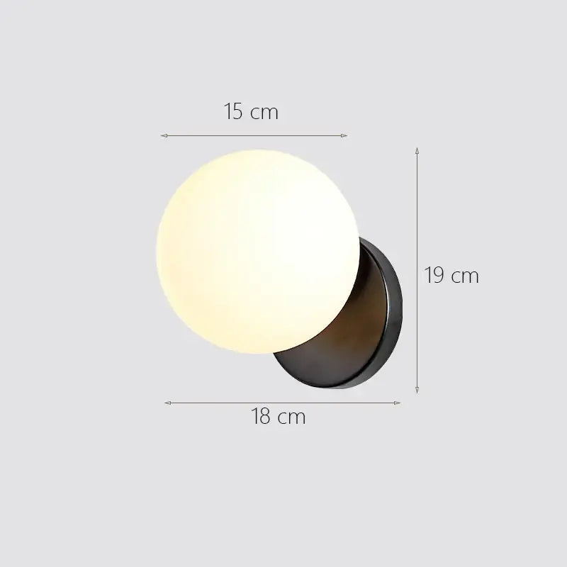 Modern gold decorbites glass ball wall lamp featuring a frosted glass globe and matte black metal base bedroom sconce