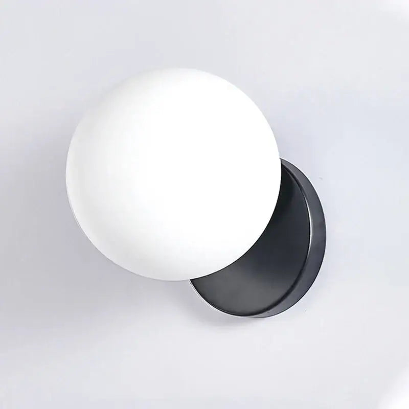 Modern gold decorbites glass ball wall lamp with matte white glass globe and sleek black metal base for bedroom sconce