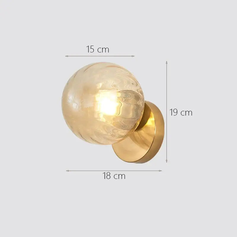 Modern gold decorbites glass ball wall lamp with a gold-toned polished brass base and textured amber glass globe