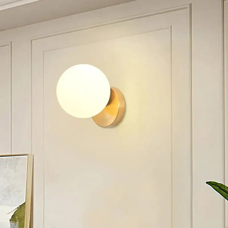 Modern gold decorbites glass ball wall lamp featuring a gold-toned spherical sconce with frosted glass globe