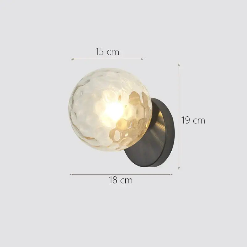 A warm textured glass ball wall lamp with a matte black metal base from decorbites for modern gold decor