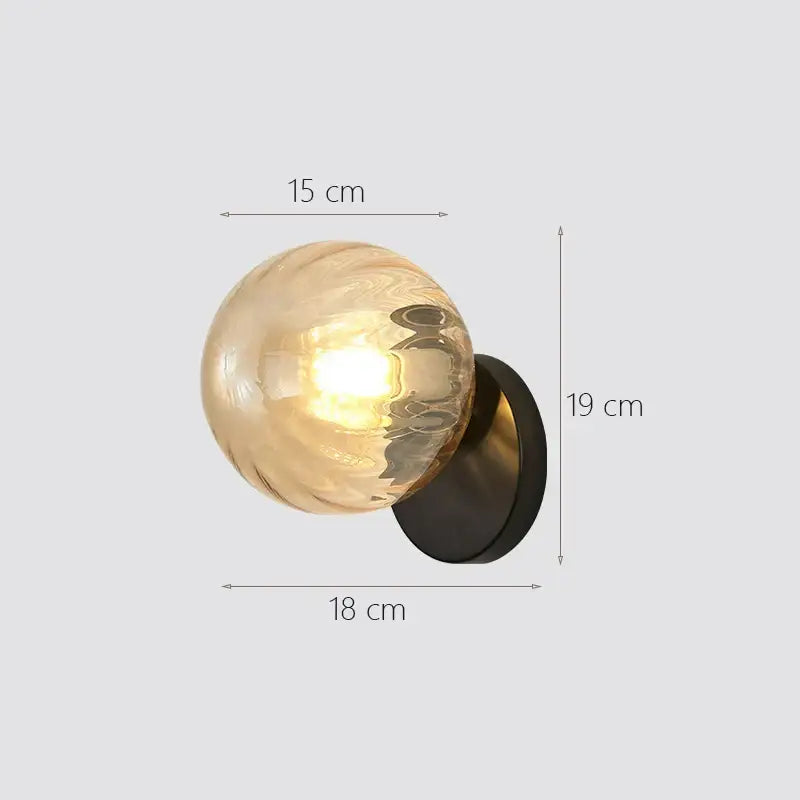 Modern gold decorbites glass ball wall lamp with a warm-toned spherical glass globe and matte black base for bedroom use