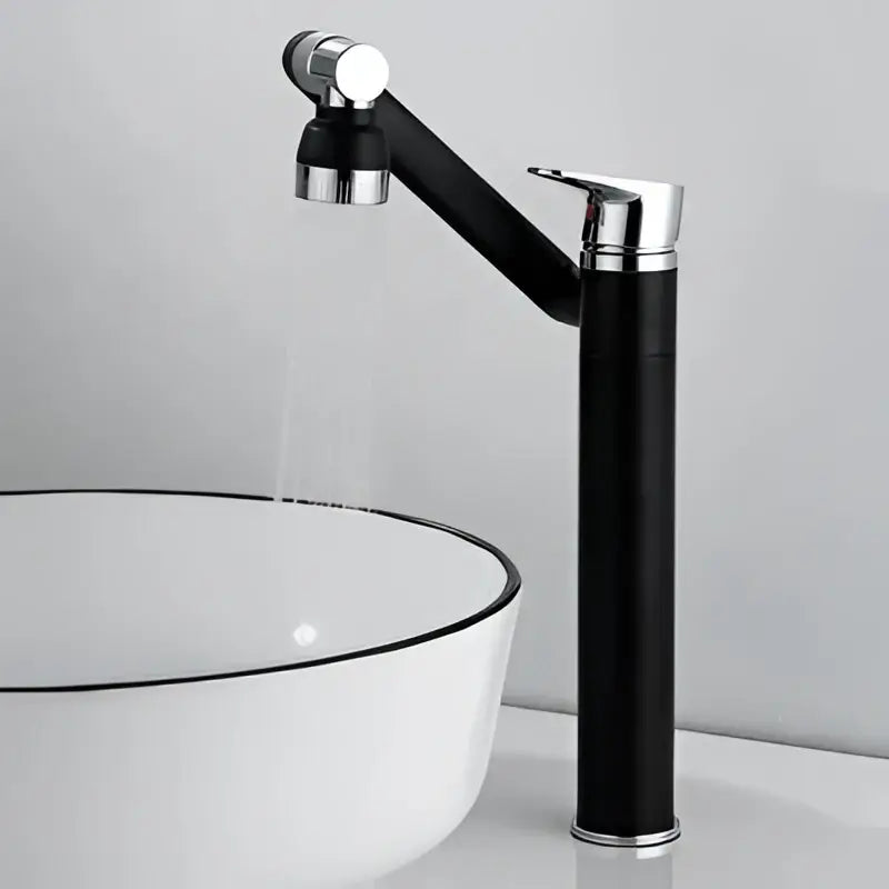 Modern gold detachable spray bathroom sink faucet with black and chrome curved spout beside white ceramic sink