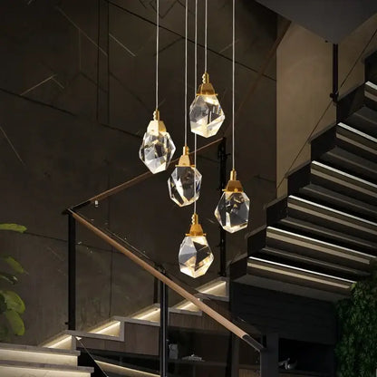 Five faceted crystal pendant lights with gold fixtures form a modern diamond crystal chandelier staircase led lighting