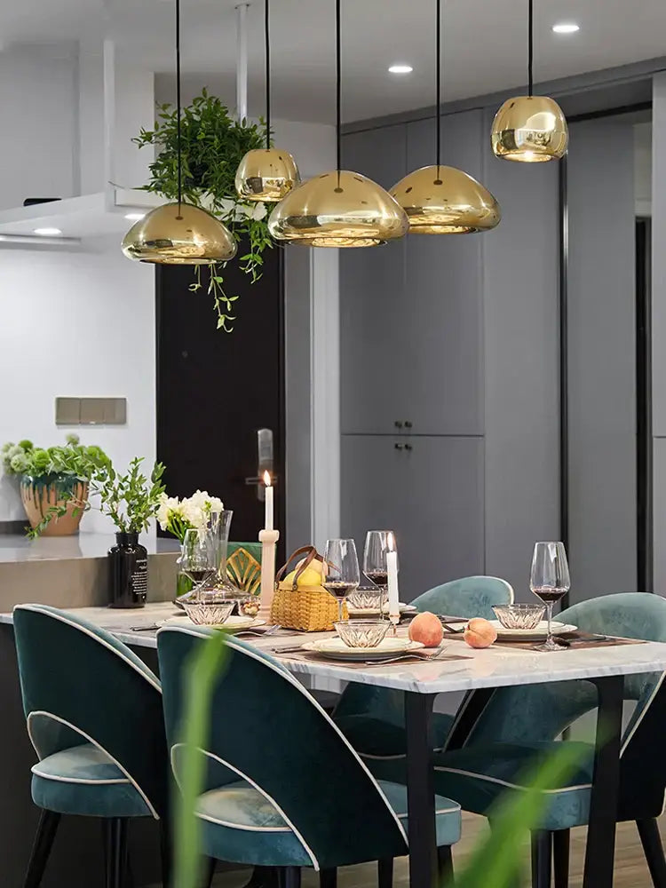 Modern gold dome pendant lamps with polished metallic surface and perforated detailing hang above dining table decorbites glass gold ceiling