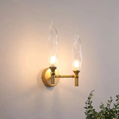 Modern gold double arm wall sconce with two flame-shaped clear glass shades for living room lighting