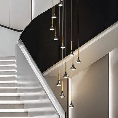 Modern gold elegant horn-shaped chandelier with black accents hanging above a sleek staircase decorbites elegant