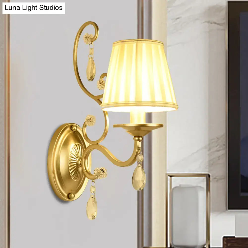 Modern gold fabric wall sconce with tapered surface, crystal accents, and cream pleated lampshade light fixture