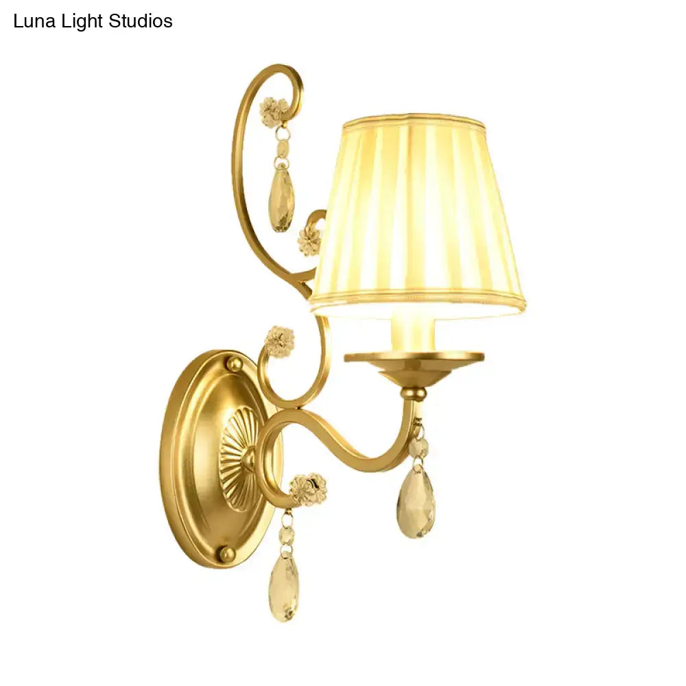 Modern gold fabric wall sconce light fixture with a tapered surface cream lampshade and crystal teardrop accents