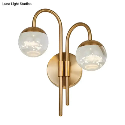 Modern gold finish wall sconce with brass curved arms and frosted glass globe shades for living room lighting