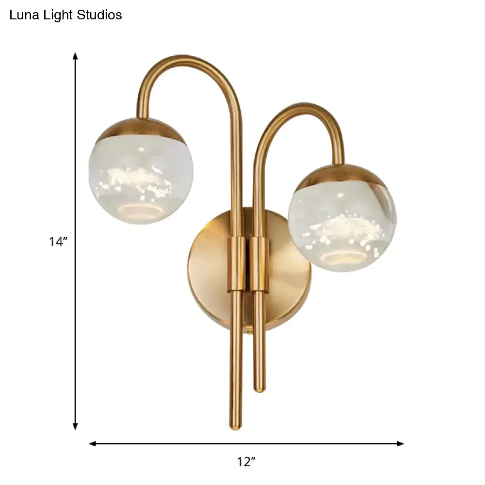 Modern gold finish wall sconce with brass-finished curved arms and frosted glass globe for living room lighting