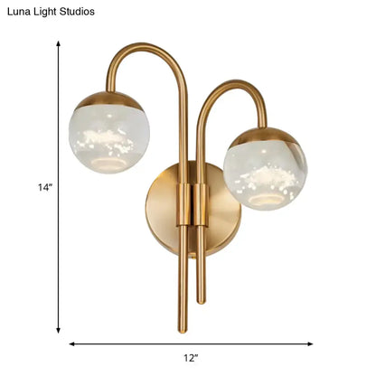 Modern gold finish wall sconce with brass-finished curved arms and frosted glass globe for living room lighting