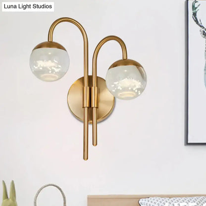 Modern gold finish wall sconce with brass curved arms and frosted glass globe shades for living room lighting