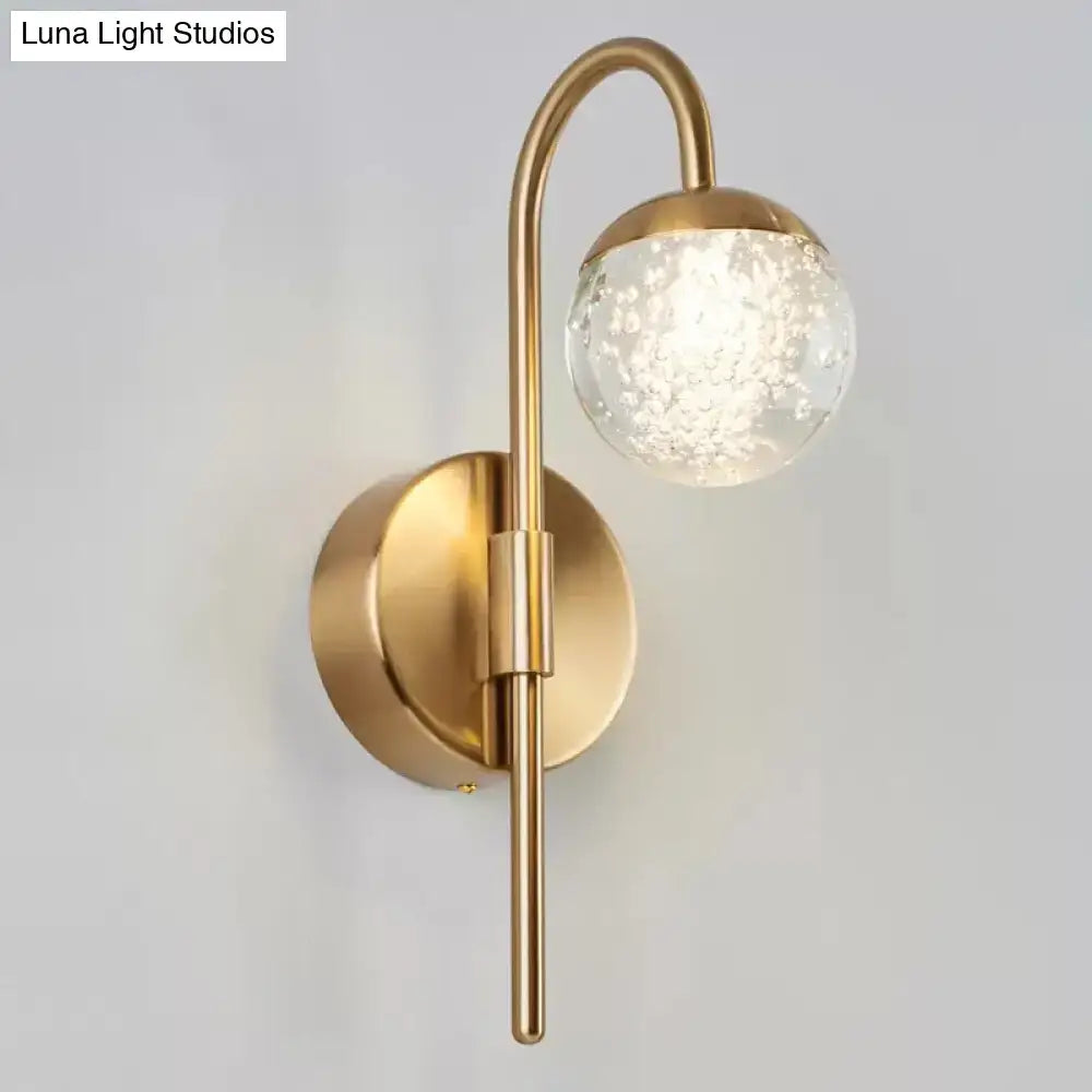 Modern gold finish wall sconce with brass body and spherical crystal globe featuring internal crackle texture for living room