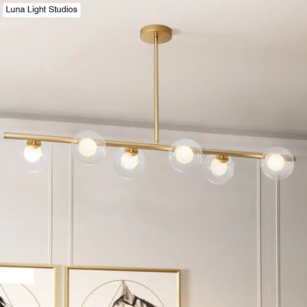 Modern gold finish linear pendant light with five clear glass globe shades for kitchen or dining areas