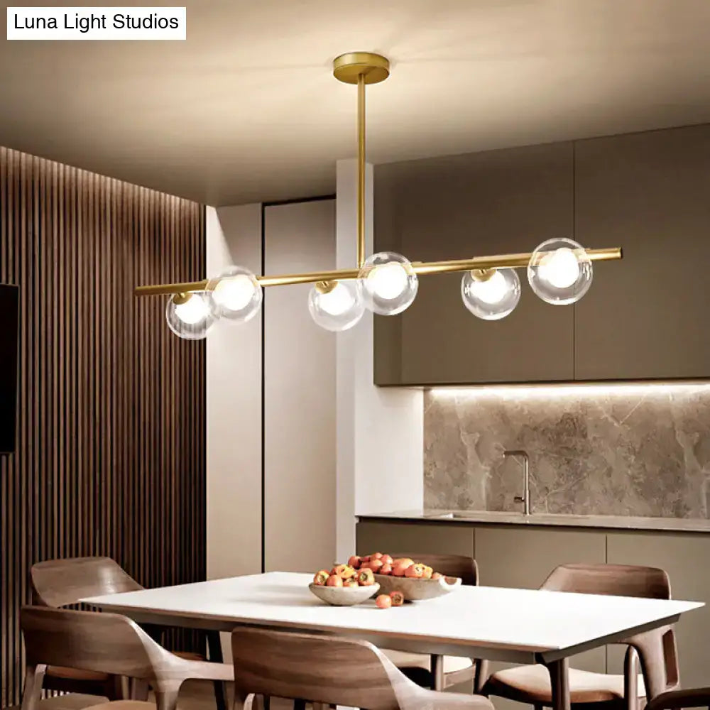 Modern gold finish linear pendant light with five clear glass globes suspended from a sleek horizontal bar