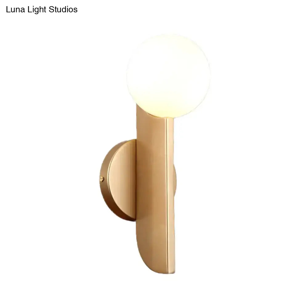 Modern gold finish wall sconce with a milky glass shade featuring a frosted globe ideal for bedroom lighting