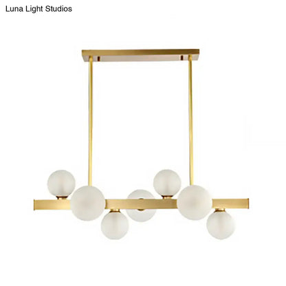 Modern gold pendant light with frosted glass globe bulbs and adjustable chain cord length for dining room island lighting