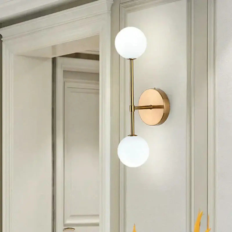 Modern gold led wall sconce with two frosted glass globe shades for bedroom lighting
