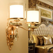 Modern gold ornate wall lamp with frosted glass shades and crystal droplets creating an inviting glow