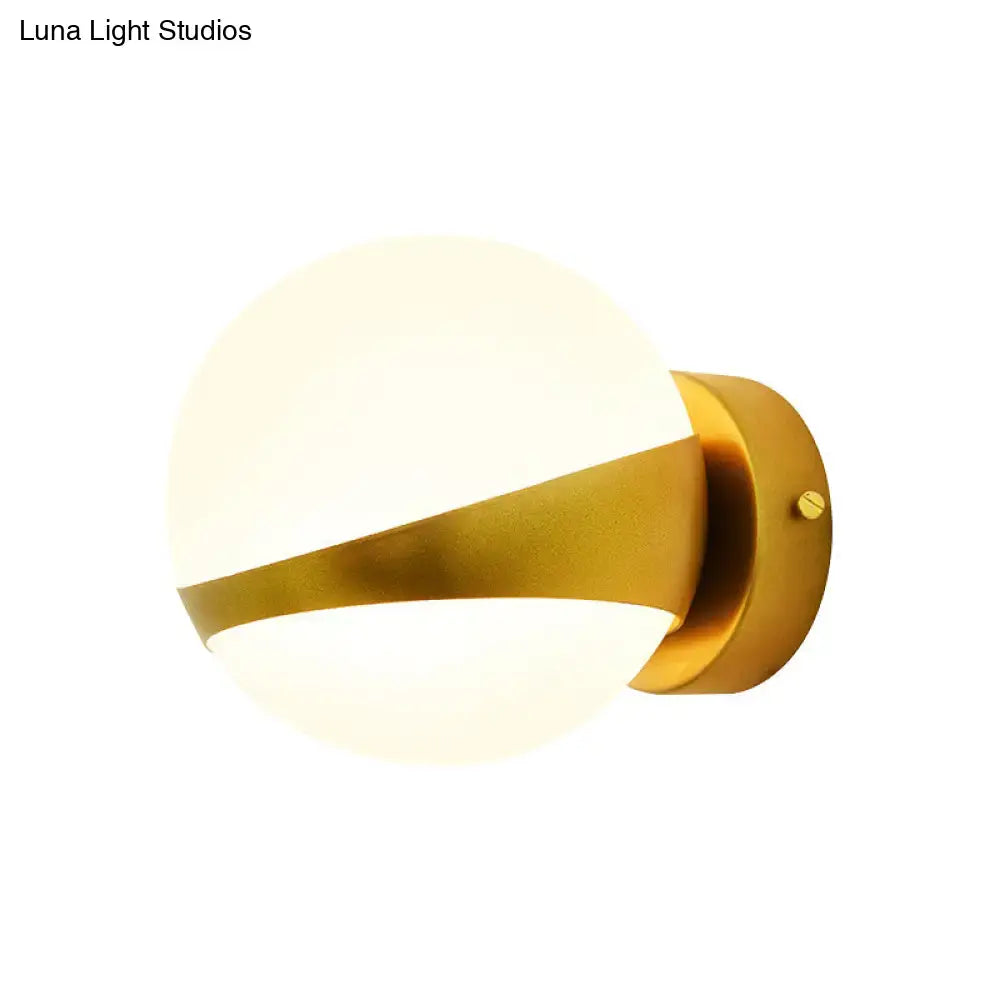 Modern gold frosted glass wall sconce with a matte white diffuser and direct wired spherical design for bedroom use
