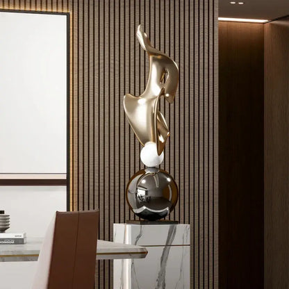 A sleek gold geometric electroplating art sculpture with flowing curves on a marble pedestal for living room decorbites