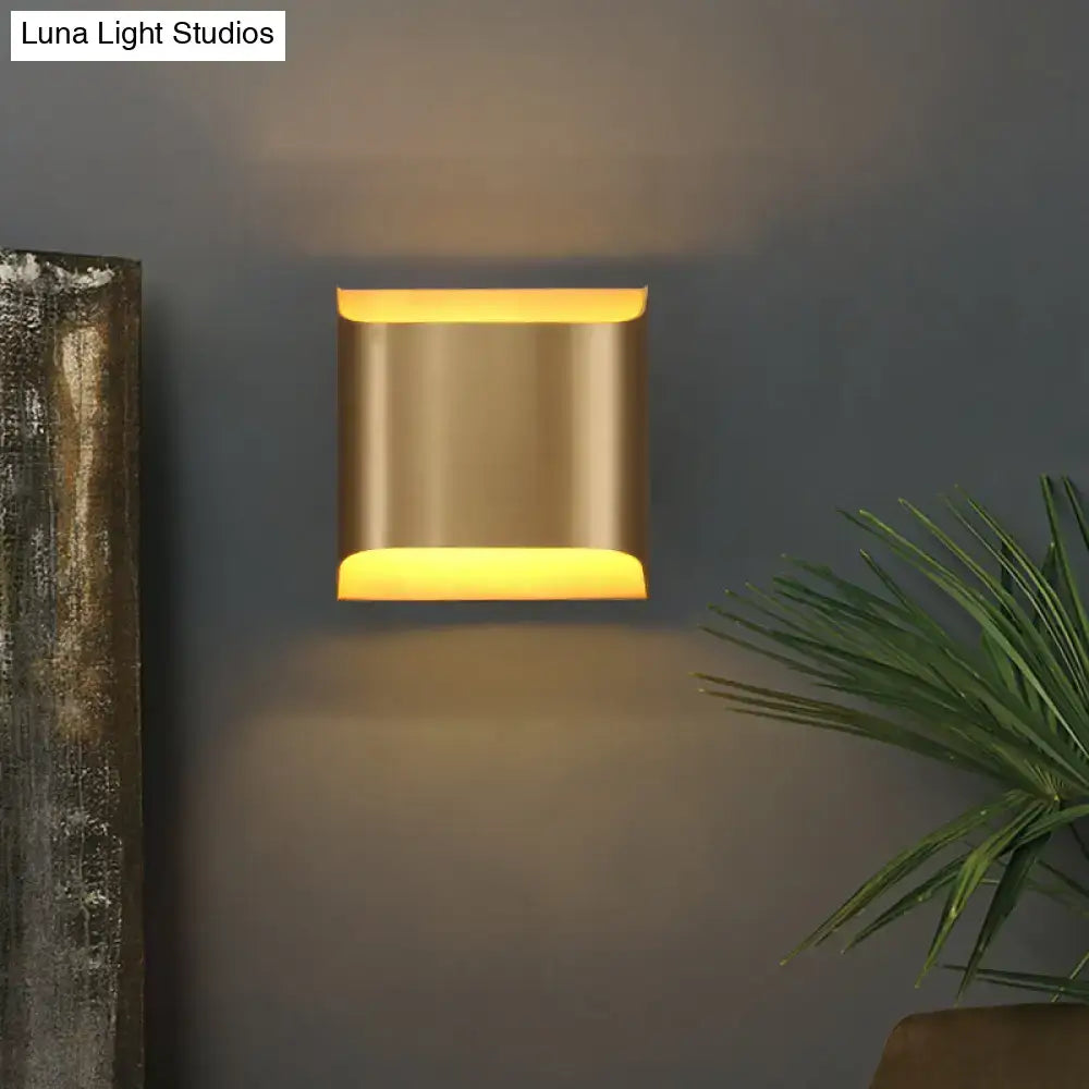 A modern gold geometric led wall sconce with brushed gold finish and g9 bulb base illuminating warm yellow light