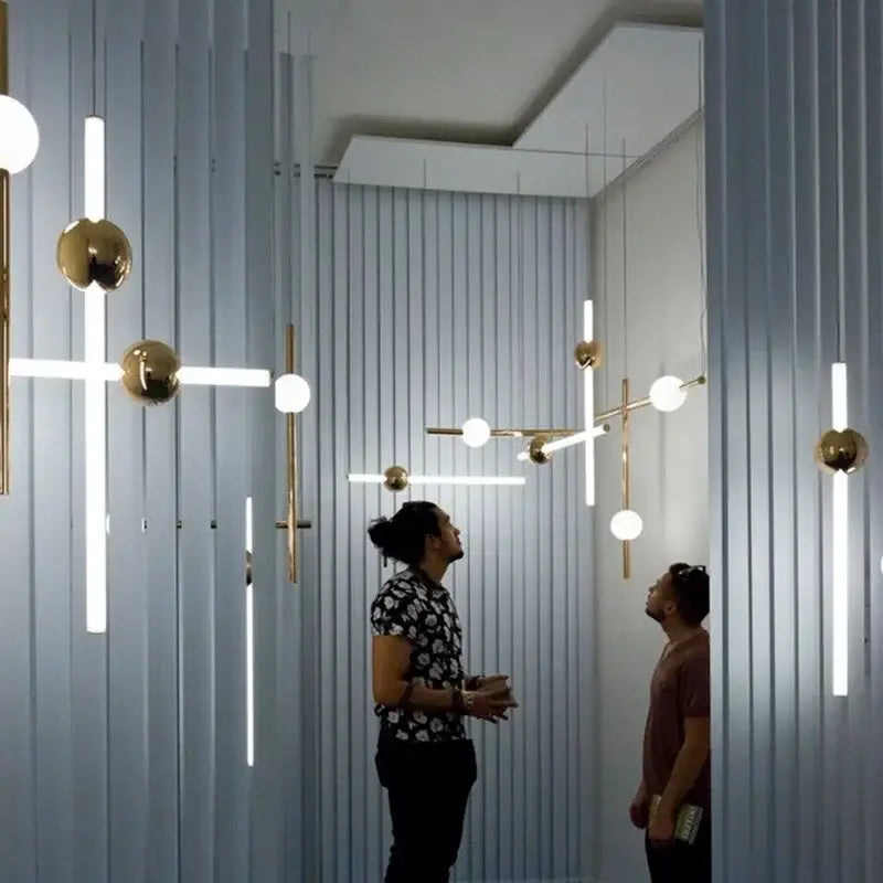 Modern gold geometric line frame pendant lights with sleek metal arms and glass globes for dining room lighting