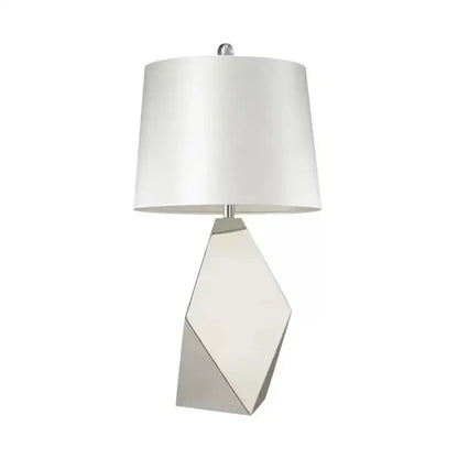 Modern geometric table lamp with a sleek silver three-dimensional geometric base and white drum shade for bedroom use