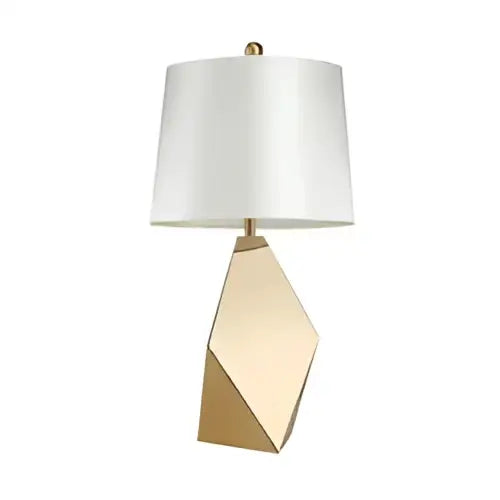 A modern gold geometric table lamp with a white fabric shade and a three-dimensional geometric base for bedroom use