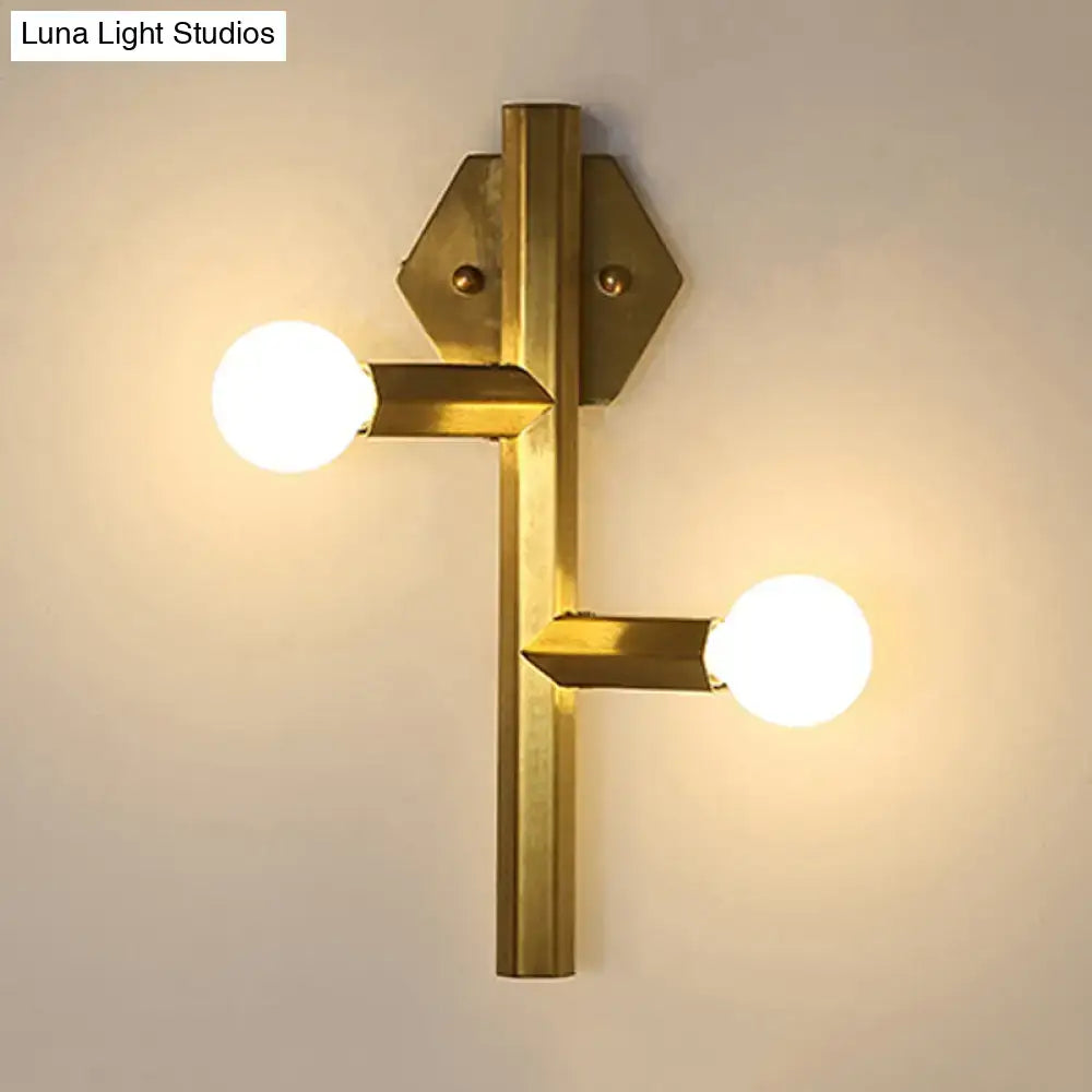 Brass-finished modern gold geometric wall light with two exposed bulbs and hexagonal mounting plates for vertical tube corner use