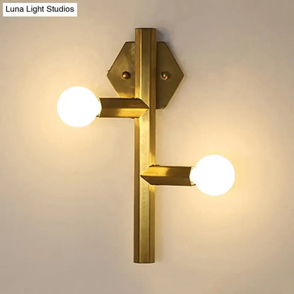 Brass-finished modern gold geometric wall light with two exposed bulbs and hexagonal mounting plates for vertical tube corner use