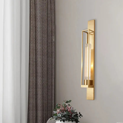 Modern gold wall mount lamp with rectangular geometric metal frame and clear ribbed glass shade for bedroom use