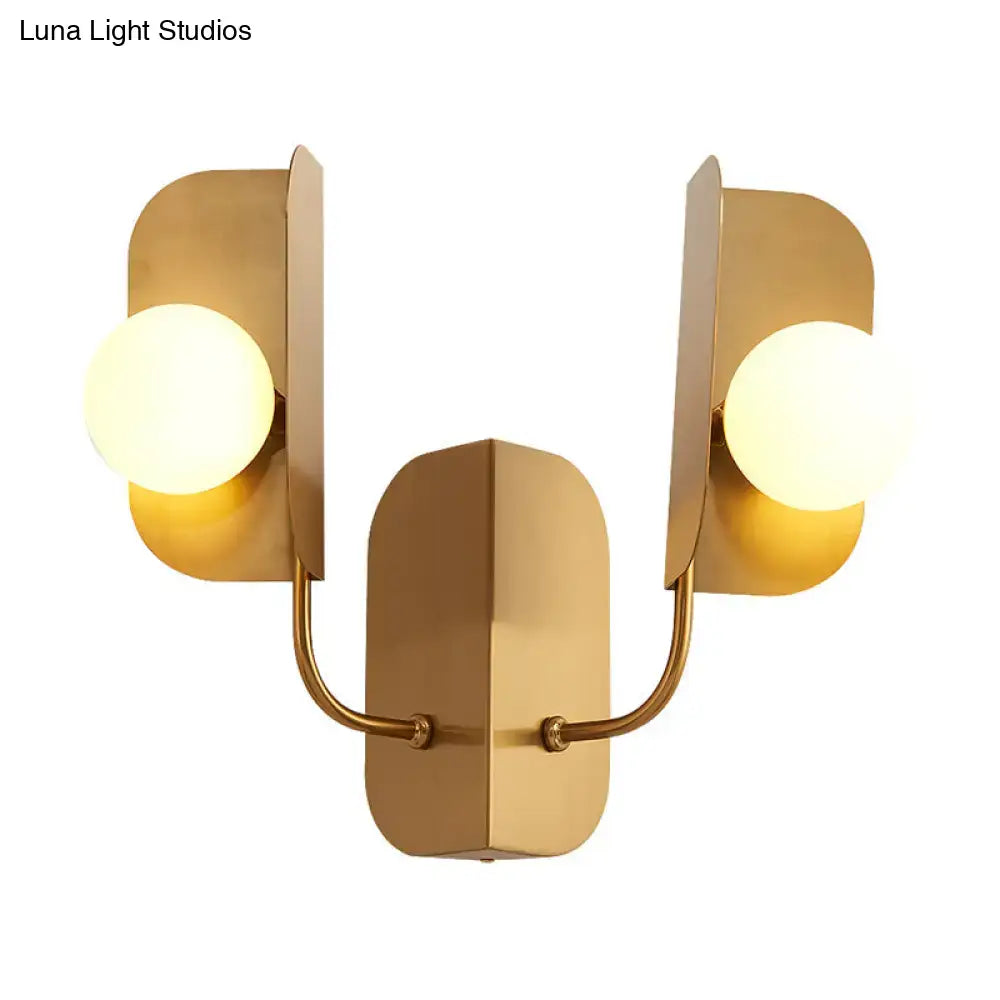 Modern gold geometric wall sconce light with two frosted glass bulbs and curved metal arms for living room use