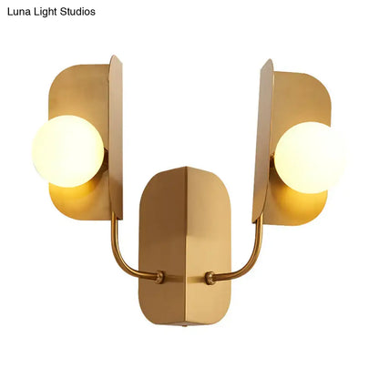 Modern gold geometric wall sconce light with two frosted glass bulbs and curved metal arms for living room use