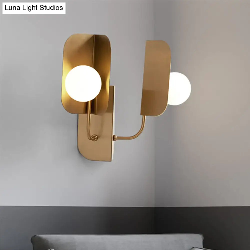 Modern gold geometric wall sconce light with two frosted glass bulbs and curved metal arms for living room use