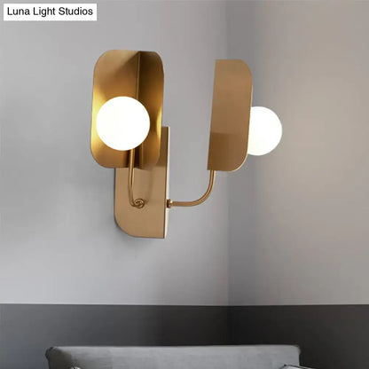 Modern gold geometric wall sconce light with two frosted glass bulbs and curved metal arms for living room use