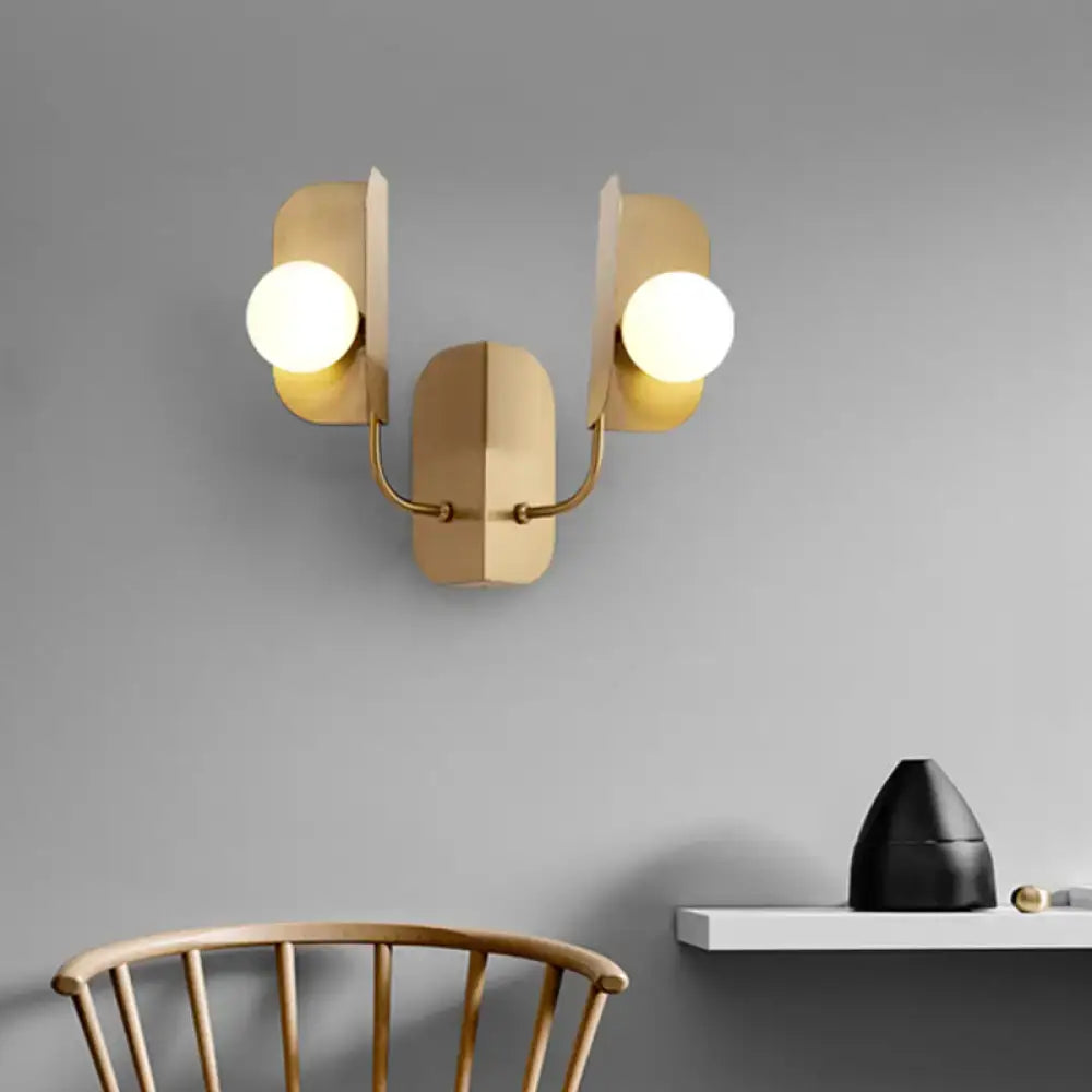 Modern gold wall sconce light with two spherical bulbs and geometric angular arms for living room use