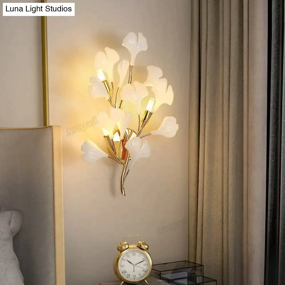 Elegant white glass ginkgo leaf wall sconce with gold-toned metal stems for modern bedroom lighting