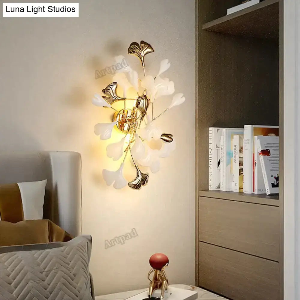 Modern gold ginkgo leaf porcelain wall sconce with gold-toned metal and delicate white and metallic ginkgo leaf accents