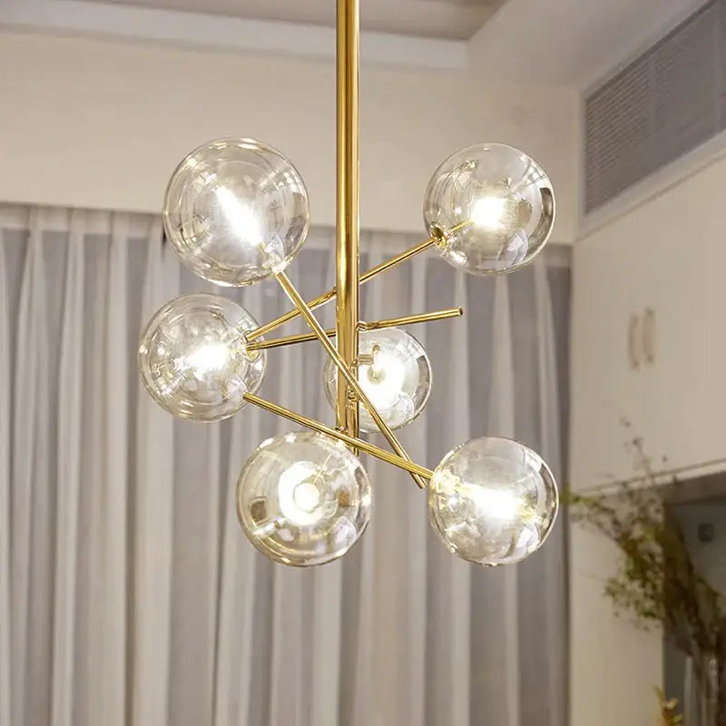 Modern gold glass ball iron chandelier with six clear glass globe bulbs in a branching starburst design by decorbites