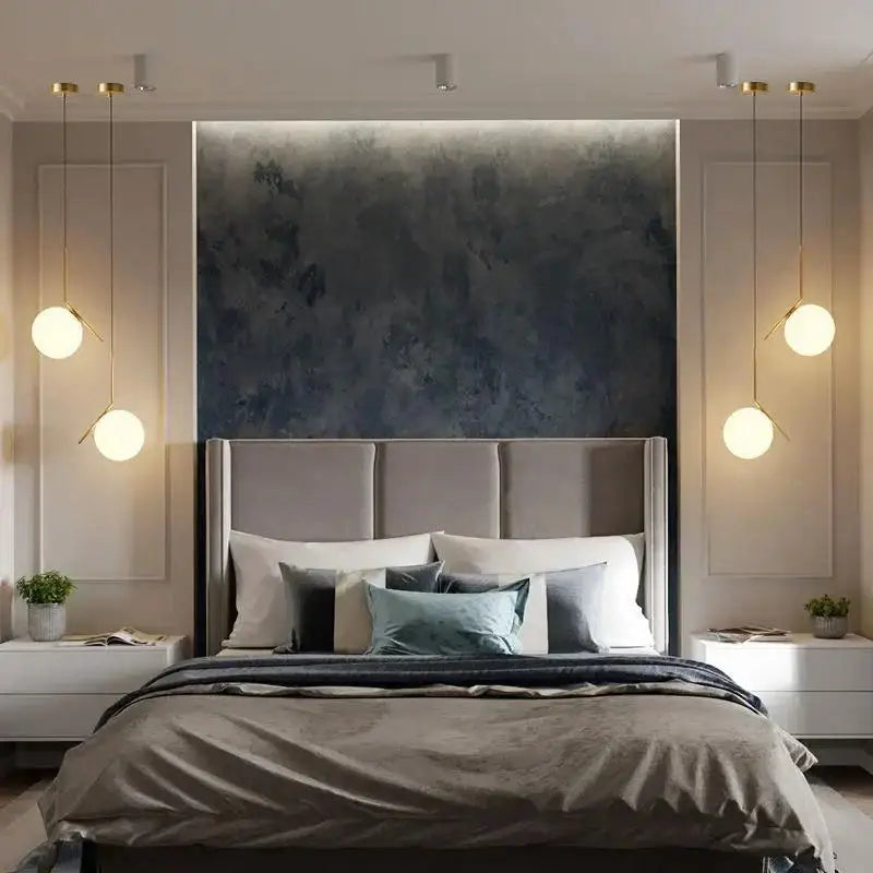 A modern bed with a tufted gray headboard and neutral bedding accented by teal pillows beneath a decorbites glass ball led pendant light