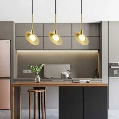 Three modern gold glass ball led pendant lights with disc-shaped shades hang above a kitchen island decorbites pendant light